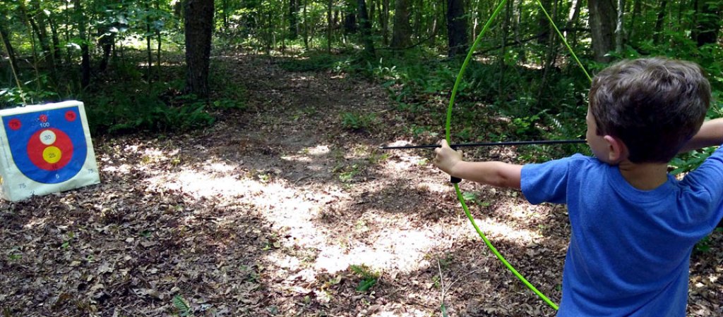 Camper steadys his aim on the archery target